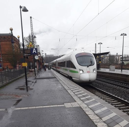 Beraterin zeigt Kundin auf Smartphone das Deutschlandticket mit Logo und erklärt Details am Schalter